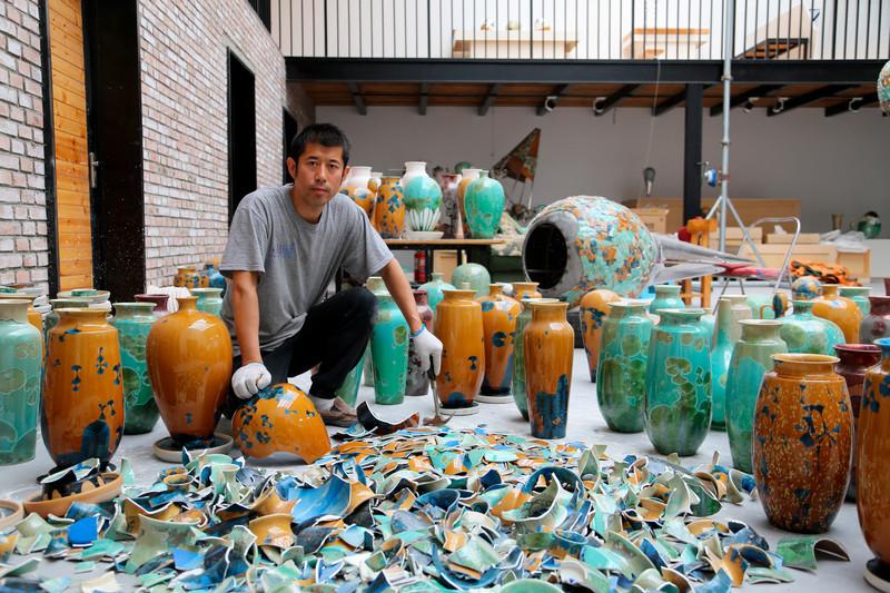 艺术家被陶瓷容器包围的照片